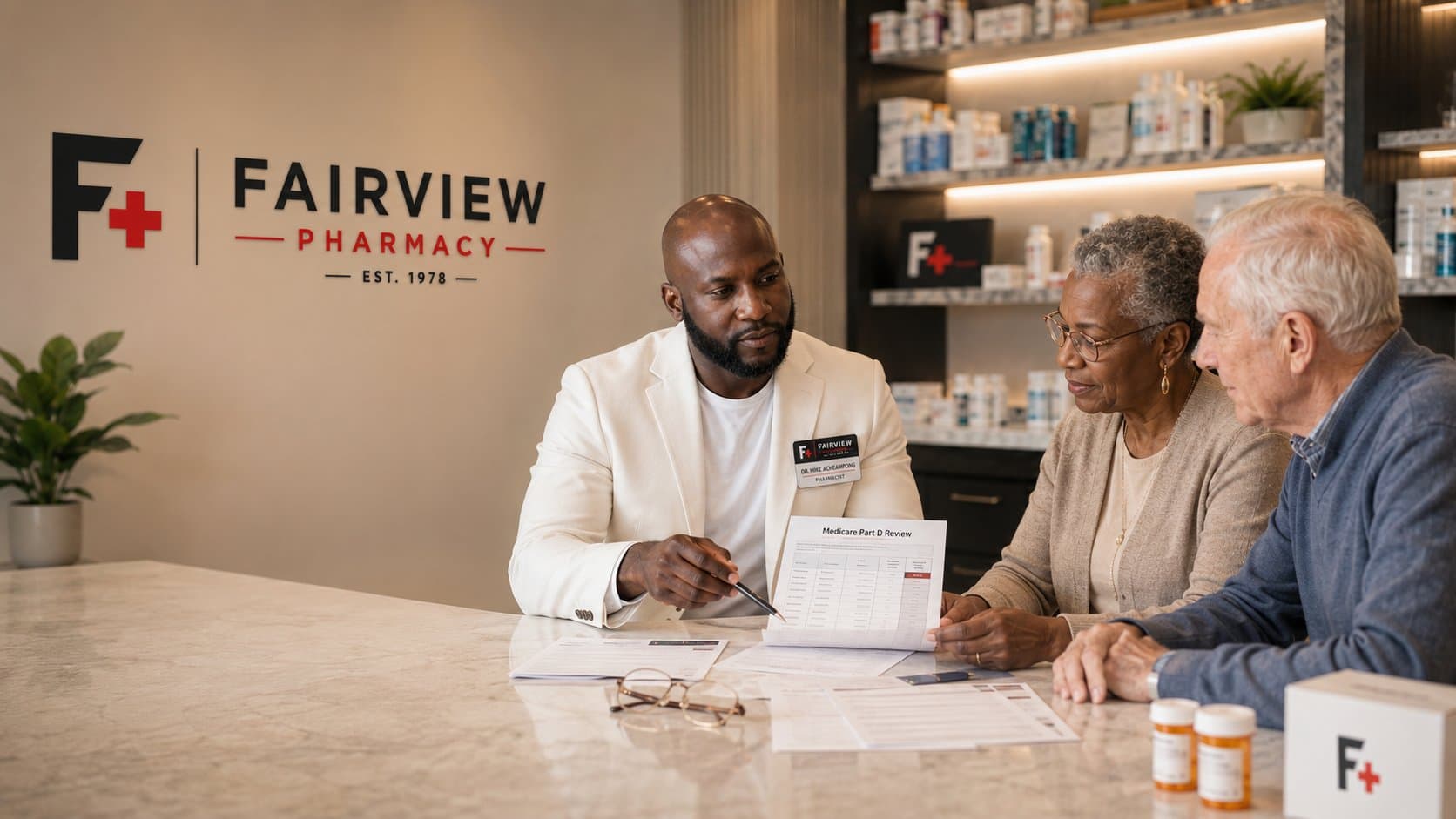 Dr. Mike Acheampong, PharmD, reviewing a Medicare Part D plan comparison sheet with a senior couple at the Fairview Pharmacy counter