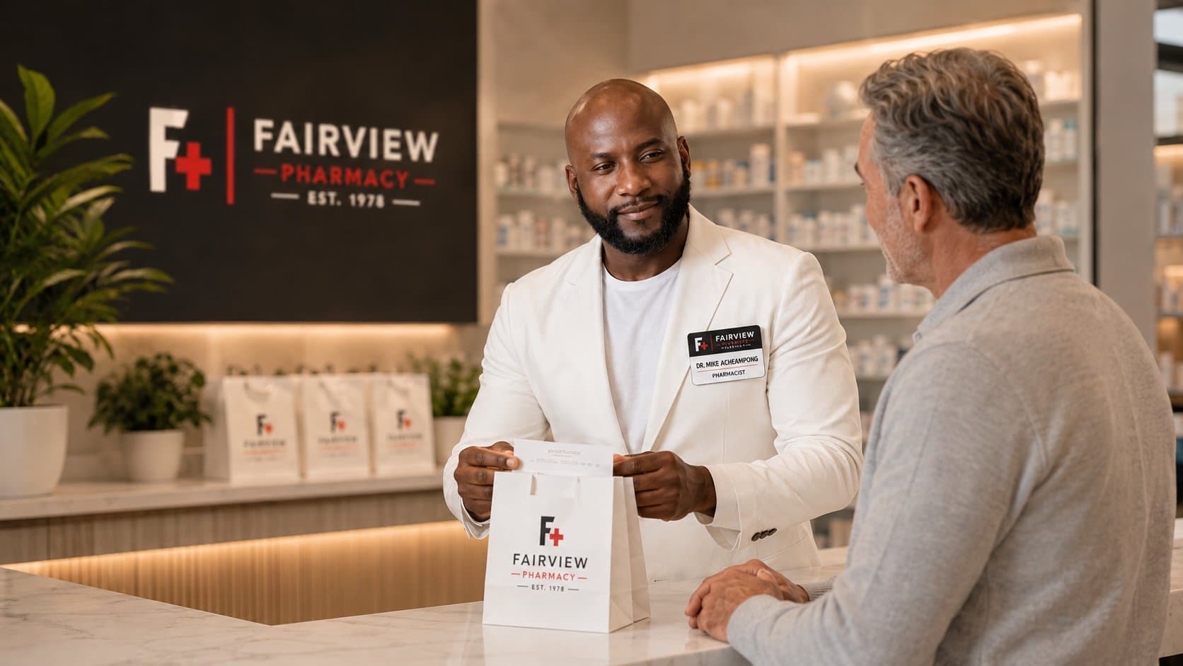 Dr. Mike Acheampong, pharmacist at Fairview Pharmacy, handing a branded Fairview prescription bag to a patient at the counter